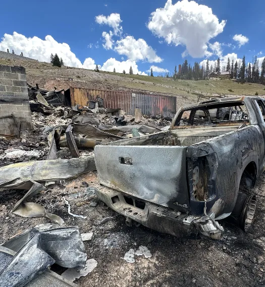 A burned-out pickup truck and scattered fire debris on the Owen family's property after the Cottonwood Fire.